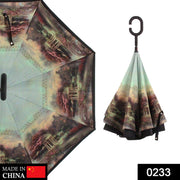 A partially open reverse umbrella with a dark landscape print, and a closed umbrella with a C-shaped handle.