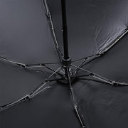 The underside of the black umbrella reveals its metal frame and ribs, supporting the dark fabric canopy.