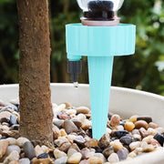 An auto plant watering device in action, slowly releasing water into a plant pot from a recycled bottle.
