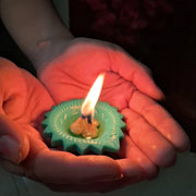 A single lit silicone diya glowing warmly on a dark surface, enhancing its festive appeal.