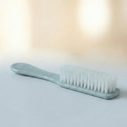 Handheld brush cleaning a shoe sole, demonstrating versatile utility