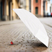 A white umbrella with a red handle stands open on a cobblestone street, ready for use.