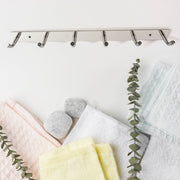 Modern home setting featuring wall mounted stainless steel coat rack with 6 hooks