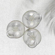 Two transparent suction hooks with strong hold on a bathroom tile wall.