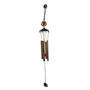 Side view of metal wind chime with Om symbol against green background
