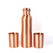 A person pouring water from the leakproof copper bottle into one of the matching glasses.