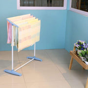 Portable clothes drying rack with towels and clothes in a balcony setting.