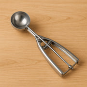 Stainless steel ice cream scoop with spring-loaded release mechanism.
