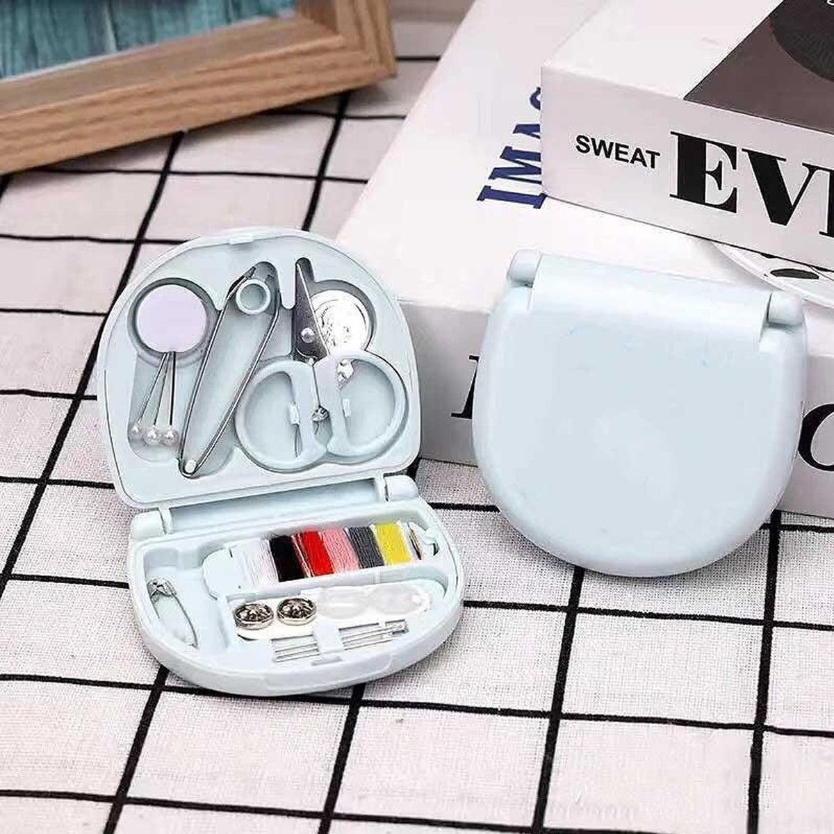 Compact Mini Travel Sewing Kit placed among other travel essentials like a passport and wallet.