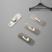Two stainless steel self-adhesive hooks neatly holding towels in a modern bathroom.