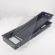 The compact charcoal cooker positioned on a picnic table, ready for grilling.