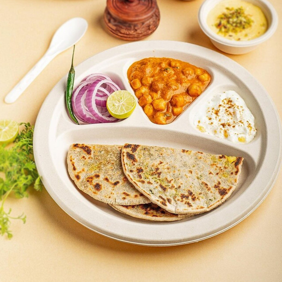 Disposable 4 compartment meal serving plate holding snacks and main course