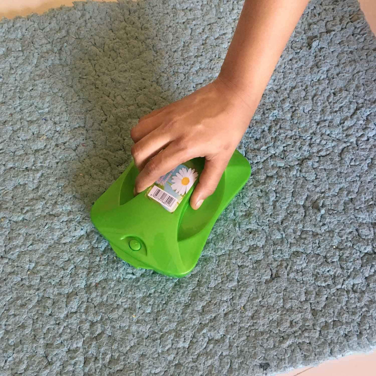 Handheld carpet roller brush efficiently cleaning dust and crumbs from a patterned rug.