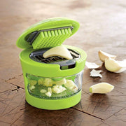 Green manual garlic crusher with a comfortable handle, perfect for kitchen use.