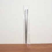 Stainless steel chopsticks actively used to pick up food during a meal.