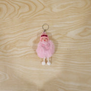 Plush doll keychain hanging on bag strap showing soft fur ball charm