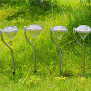 Four diamond solar garden lights creating a glowing boundary along a green lawn
