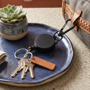 Durable retractable keychain hanging from a bag strap for easy access.