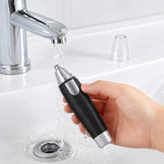Ear and nose hair trimmer displayed next to AA batteries, showing its power source.