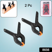 A spring clamp holding a mobile phone screen in place during repair work.