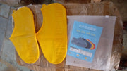 A packaged waterproof silicone shoe cover product is visible through clear plastic, showing a person wearing a blue cover.