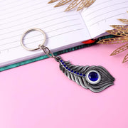 Silver-toned metal peacock feather keychain displayed on white background