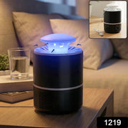 A black and white Mosquito Killer Lamp with a blue light on a wooden nightstand, with a glass of water and a book nearby.