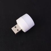 Mini portable yellow USB LED night light glowing beside a laptop keyboard